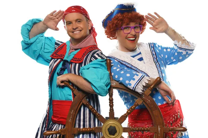 Two people dressed as pirates with a ship wheel
