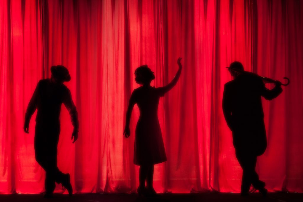 Silhouettes of three performers on a stage
